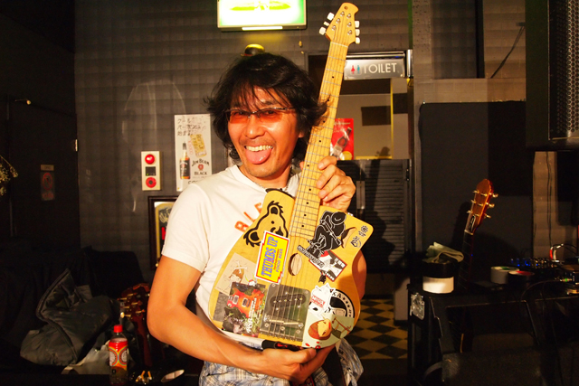 奈良さんシールが貼られたチャボさんのギターを手にするクソガキ。撮影、チャボさんのギターテック、マサミさん。